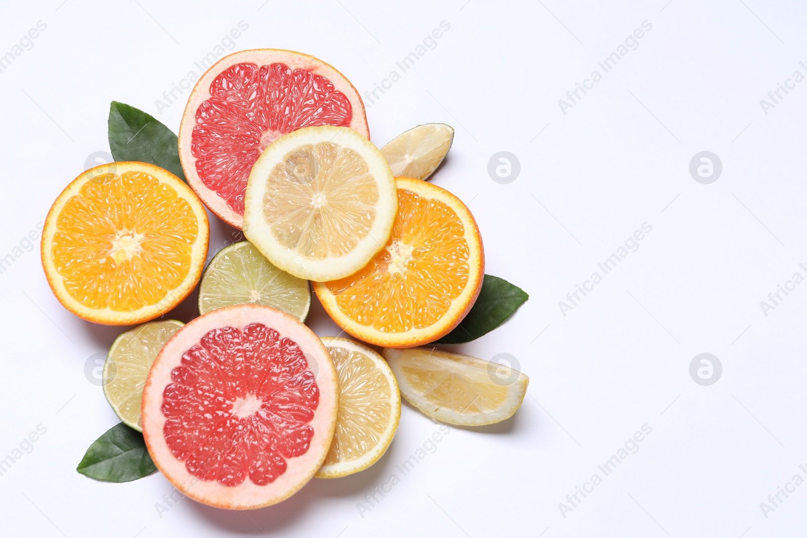 Photo of Different cut citrus fruits and leaves on white table, flat lay. Space for text