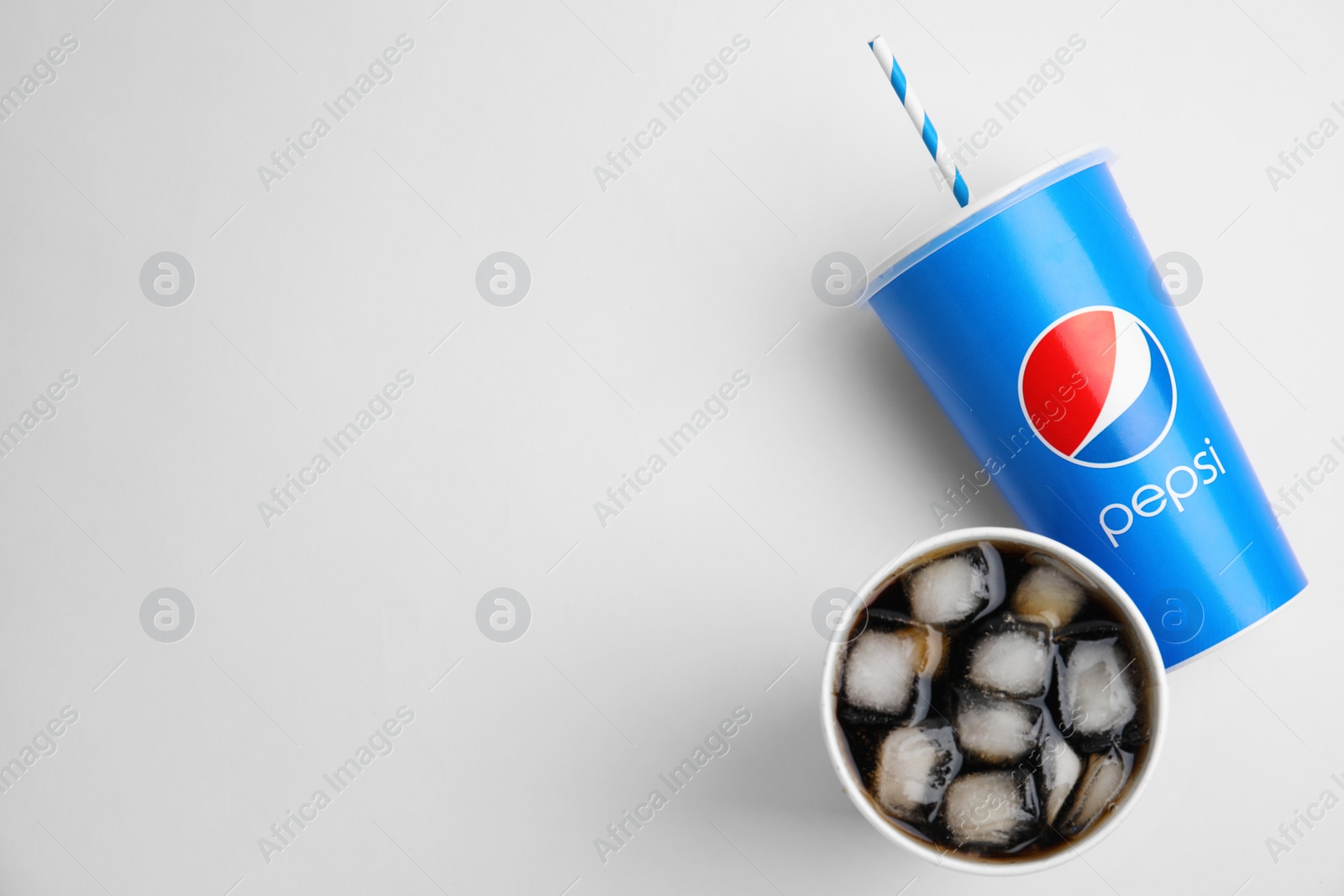 Photo of MYKOLAIV, UKRAINE - JUNE 9, 2021: Paper Pepsi cups with ice cubes on light background, flat lay. Space for text