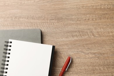 Photo of Notebooks and pen on wooden table, flat lay. Space for text