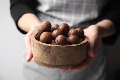 Woman holding bowl with delicious macadamia nuts, closeup