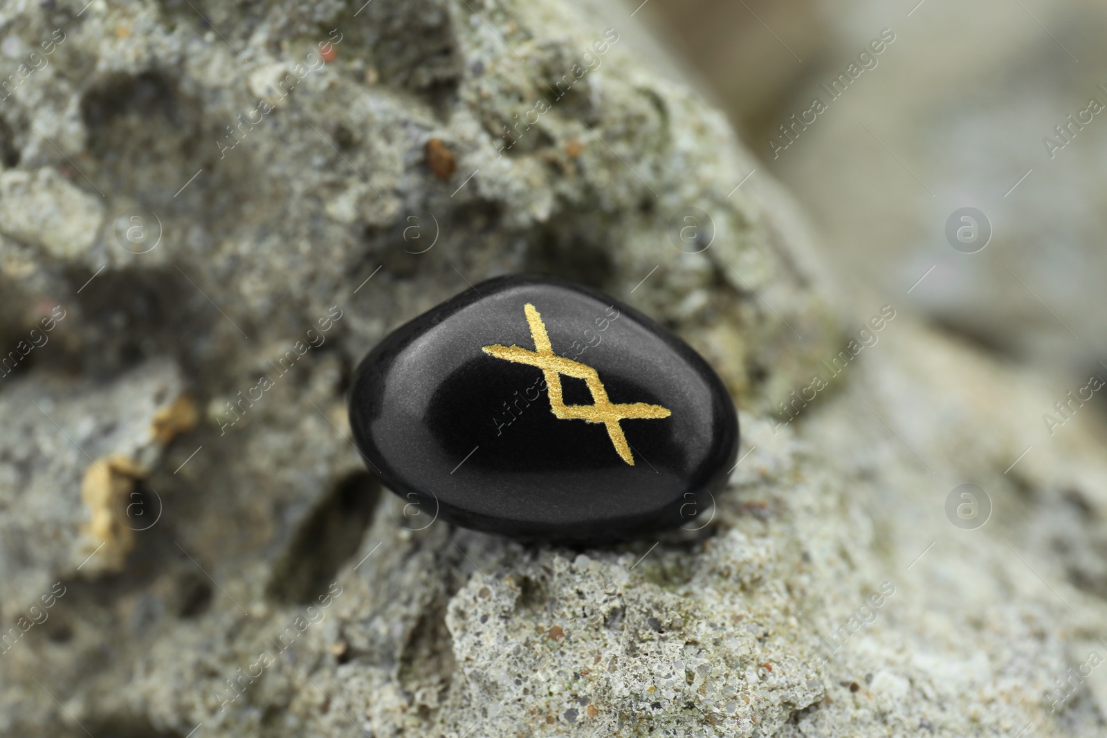 Photo of Black rune Inguz on stone outdoors, closeup