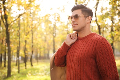 Handsome man walking in park on autumn day