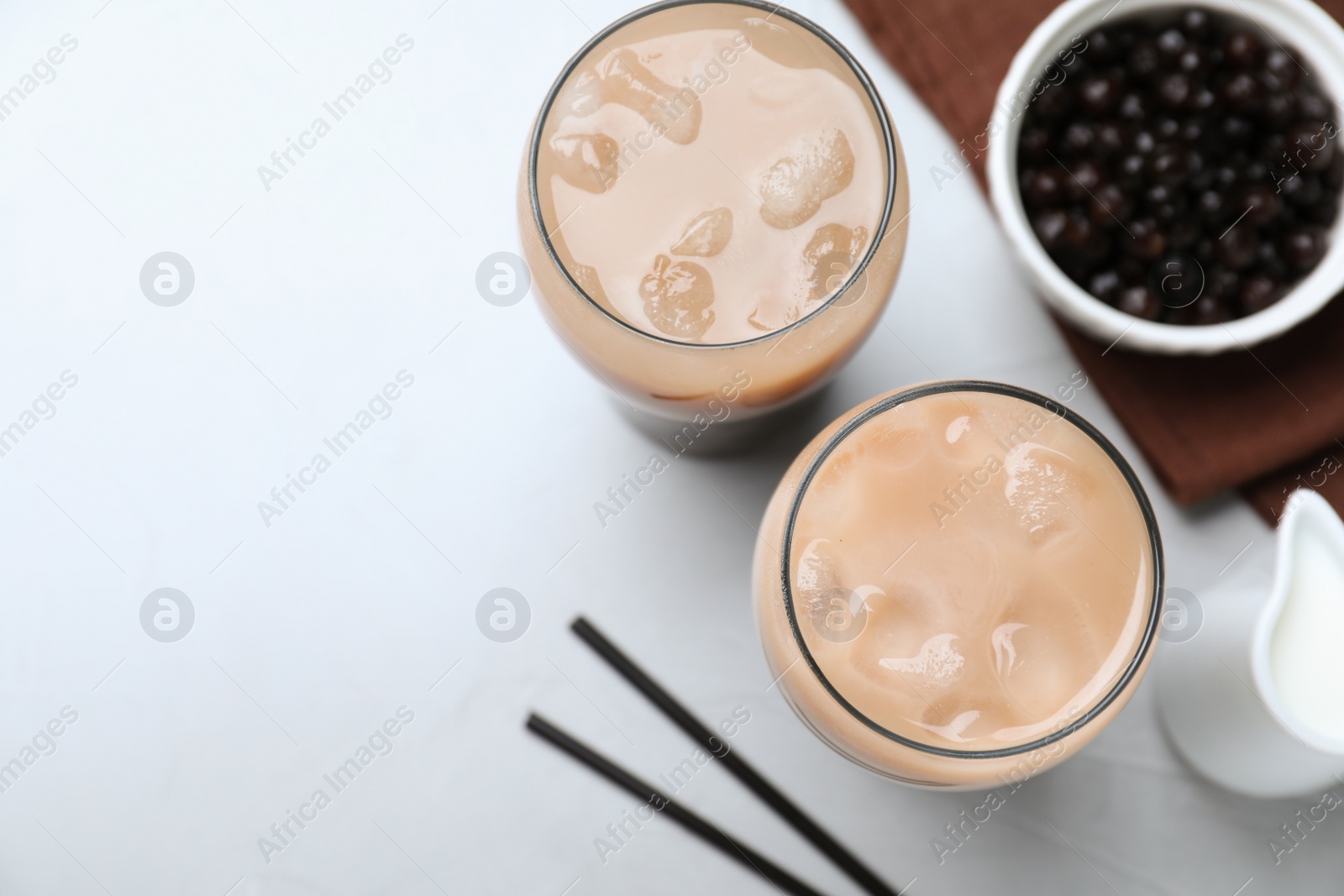 Photo of Bubble milk tea and bowl with tapioca balls on light grey table, flat lay. Space for text