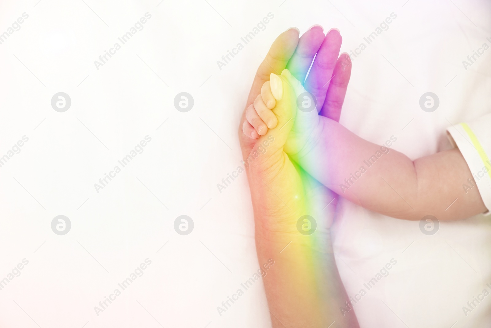 Image of National rainbow baby day. Mother with her little child on bed, closeup view of hands. Space for text