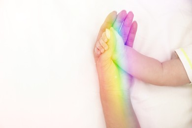 Image of National rainbow baby day. Mother with her little child on bed, closeup view of hands. Space for text