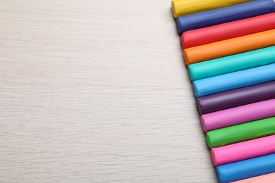 Photo of Pieces of colorful plasticine on wooden table, flat lay. Space for text