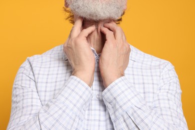 Photo of Senior man suffering from sore throat on yellow background, closeup. Cold symptoms