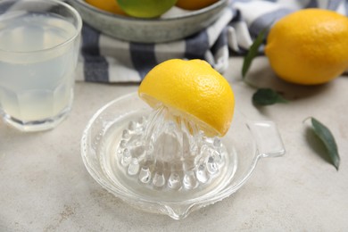 Photo of Glass squeezer with lemon and juice on light table, closeup