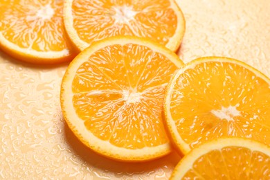 Photo of Slices of juicy orange and water on beige background, closeup