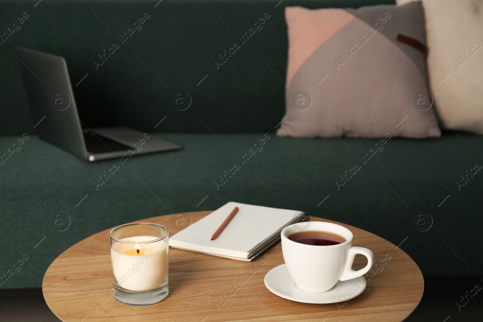 Photo of Wooden side table near sofa with laptop in room. Interior design