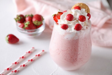 Tasty strawberry milk shake in glass on white table