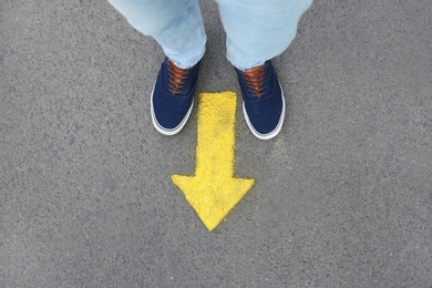 Photo of Man standing near arrow on asphalt, top view