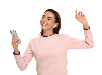 Photo of Happy young woman with smartphone listening to music through wireless earphones on white background