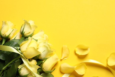 Photo of Beautiful roses, petals and ribbon on yellow background, flat lay. Space for text