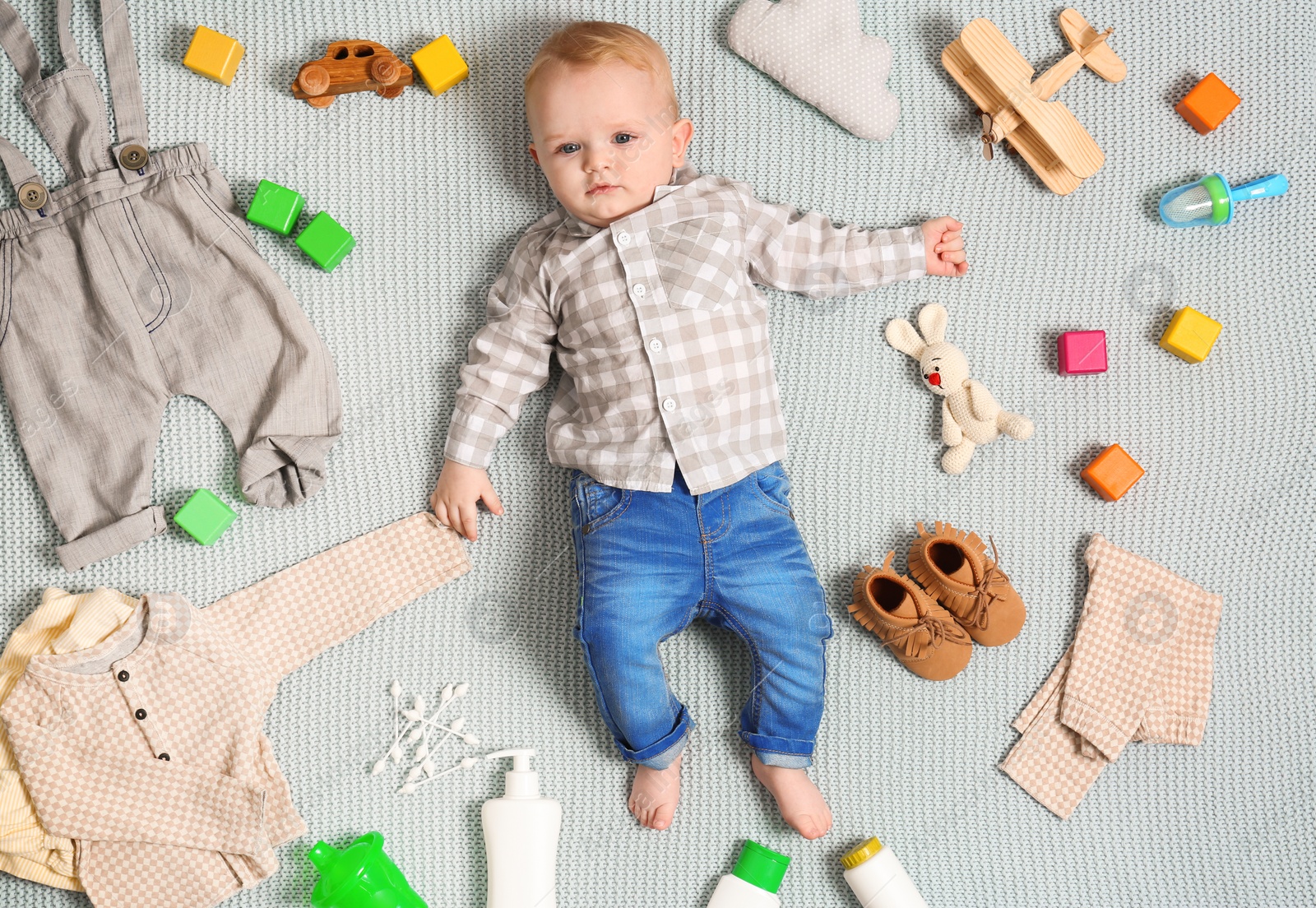 Photo of Cute little baby with clothing and accessories on color blanket, top view