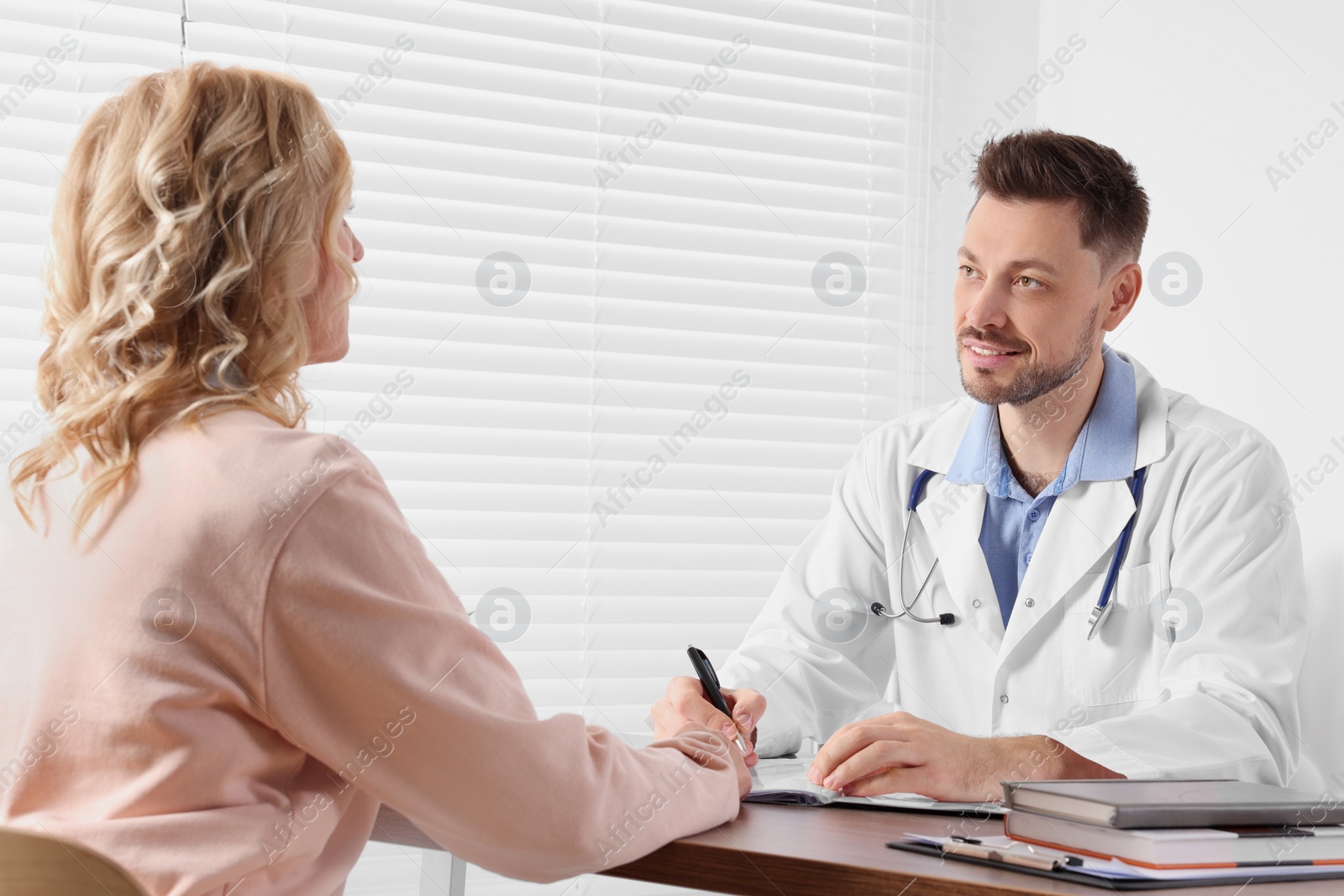 Photo of Doctor consulting patient at table in clinic