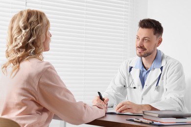 Photo of Doctor consulting patient at table in clinic