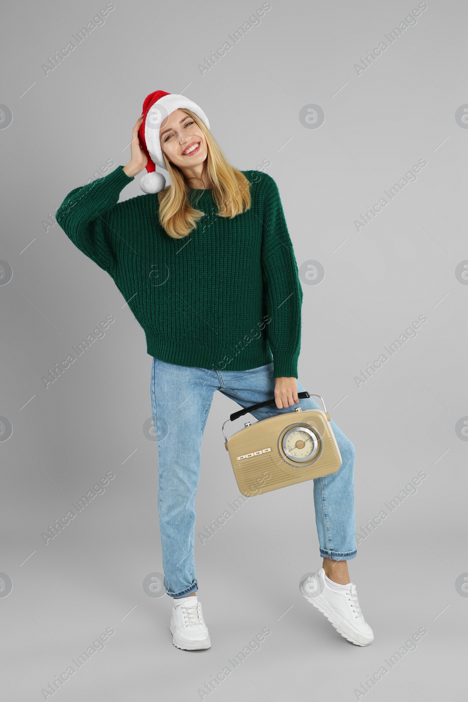 Photo of Happy woman with vintage radio on grey background. Christmas music