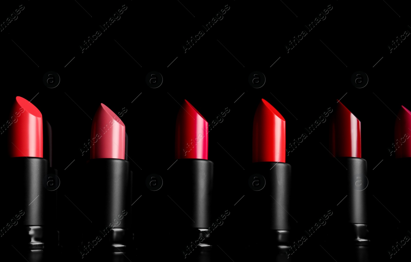 Photo of Many different bright lipsticks on black background