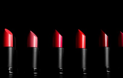 Photo of Many different bright lipsticks on black background