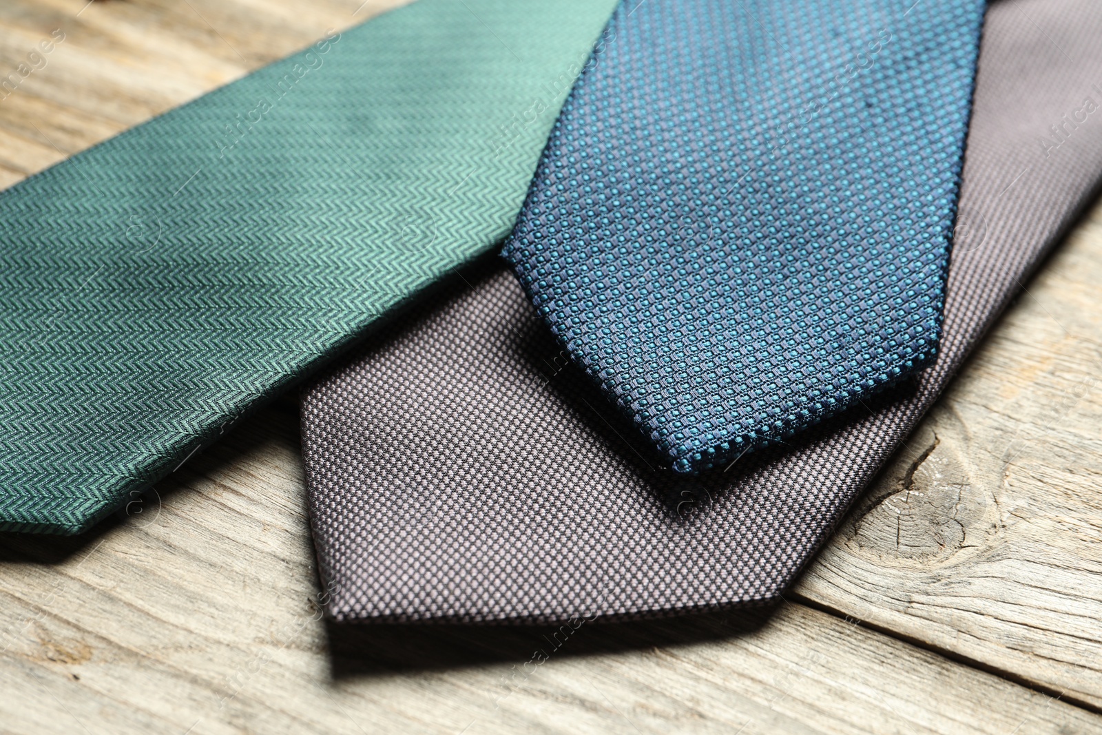 Photo of Different neckties on light wooden table, closeup