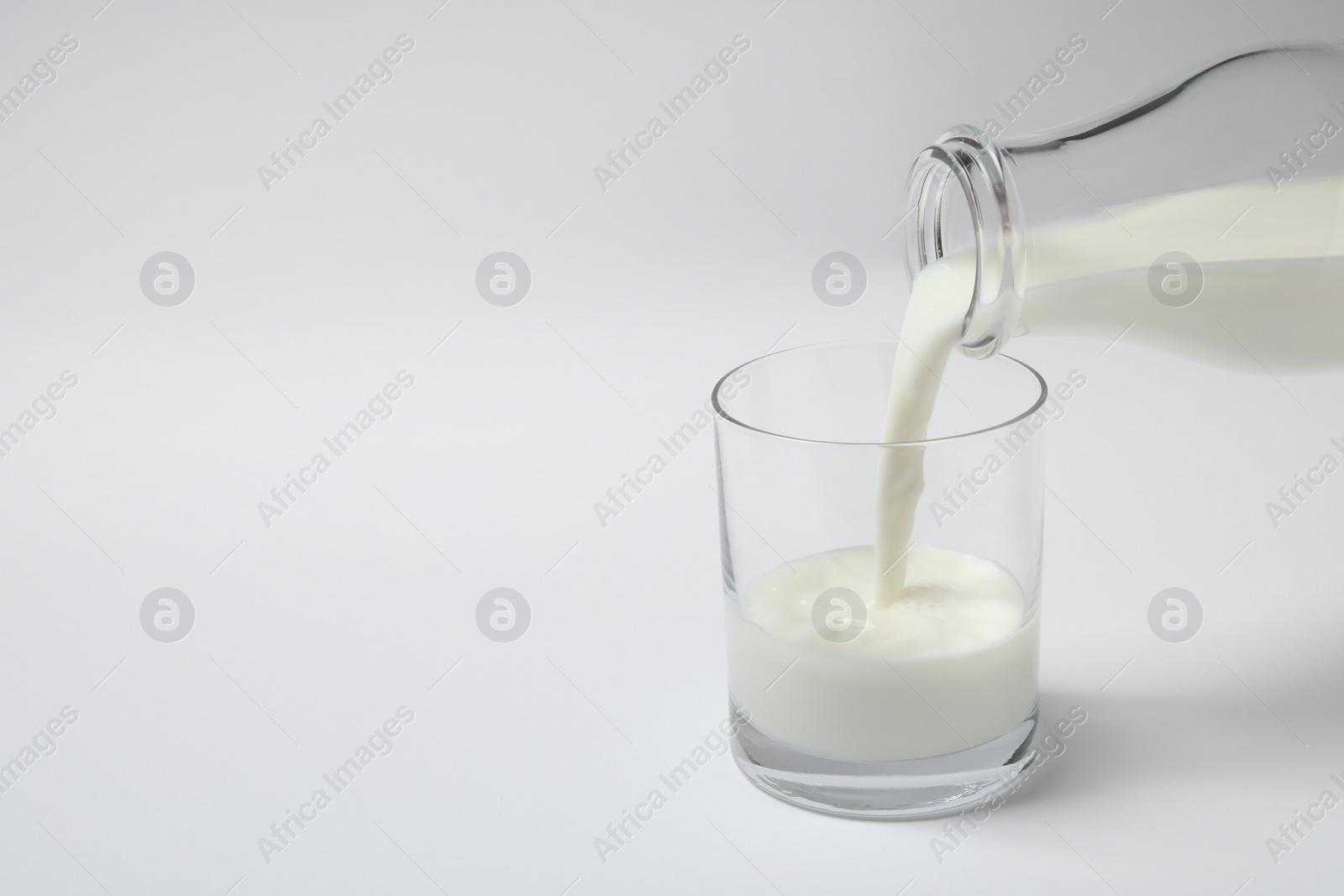 Photo of Pouring milk into glass on white background