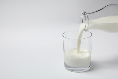 Photo of Pouring milk into glass on white background