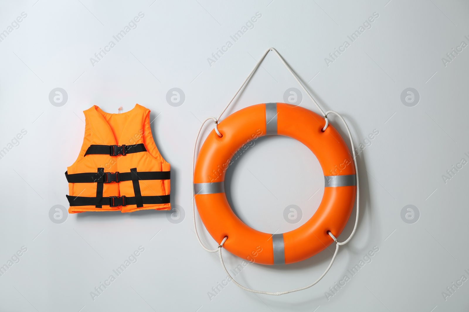 Photo of Orange life jacket and lifebuoy on light background. Rescue equipment