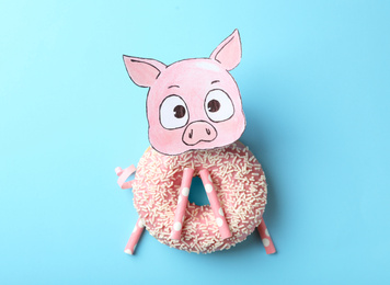 Photo of Funny pig made with donut and straws on light blue background, flat lay