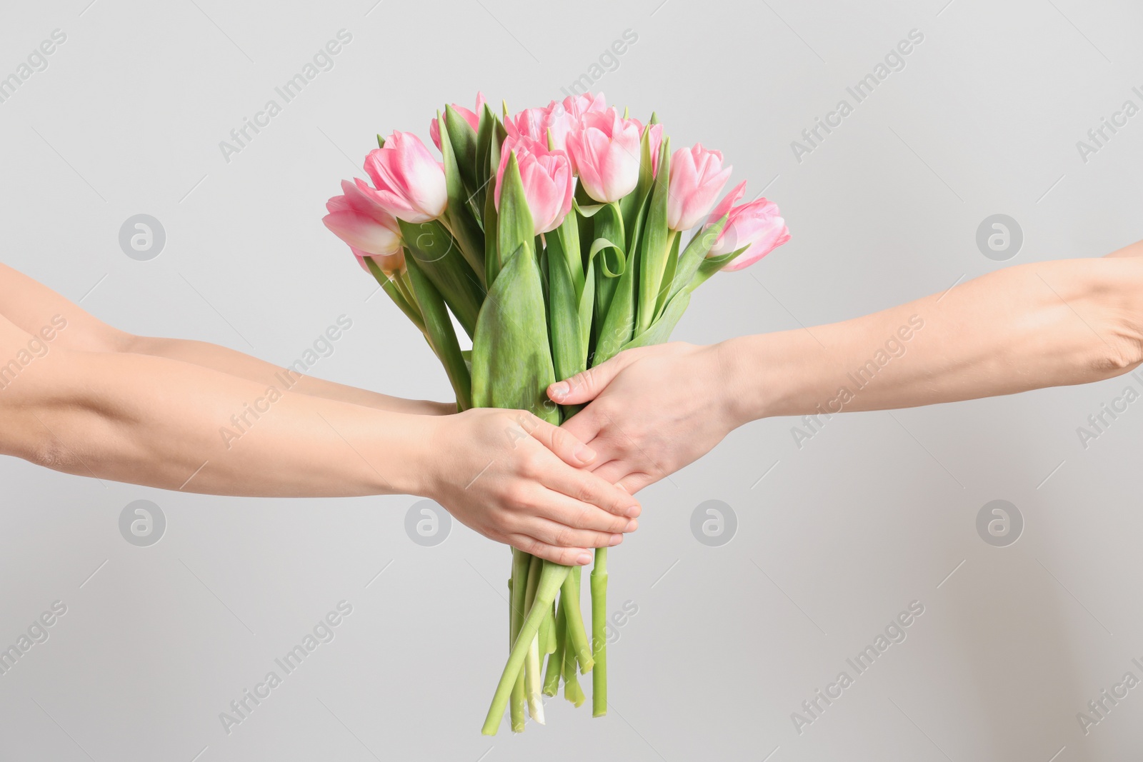 Photo of Man and lady holding bouquet of beautiful spring tulips on light background, closeup. International Women's Day