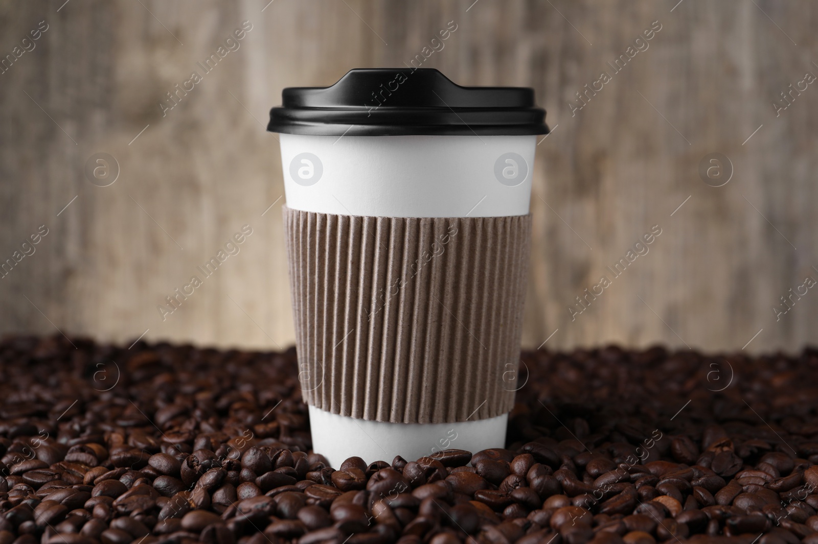 Photo of Coffee to go. Paper cup on roasted beans, closeup