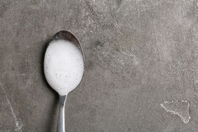 Photo of Chemical reaction of vinegar and baking soda in spoon on table, top view. Space for text