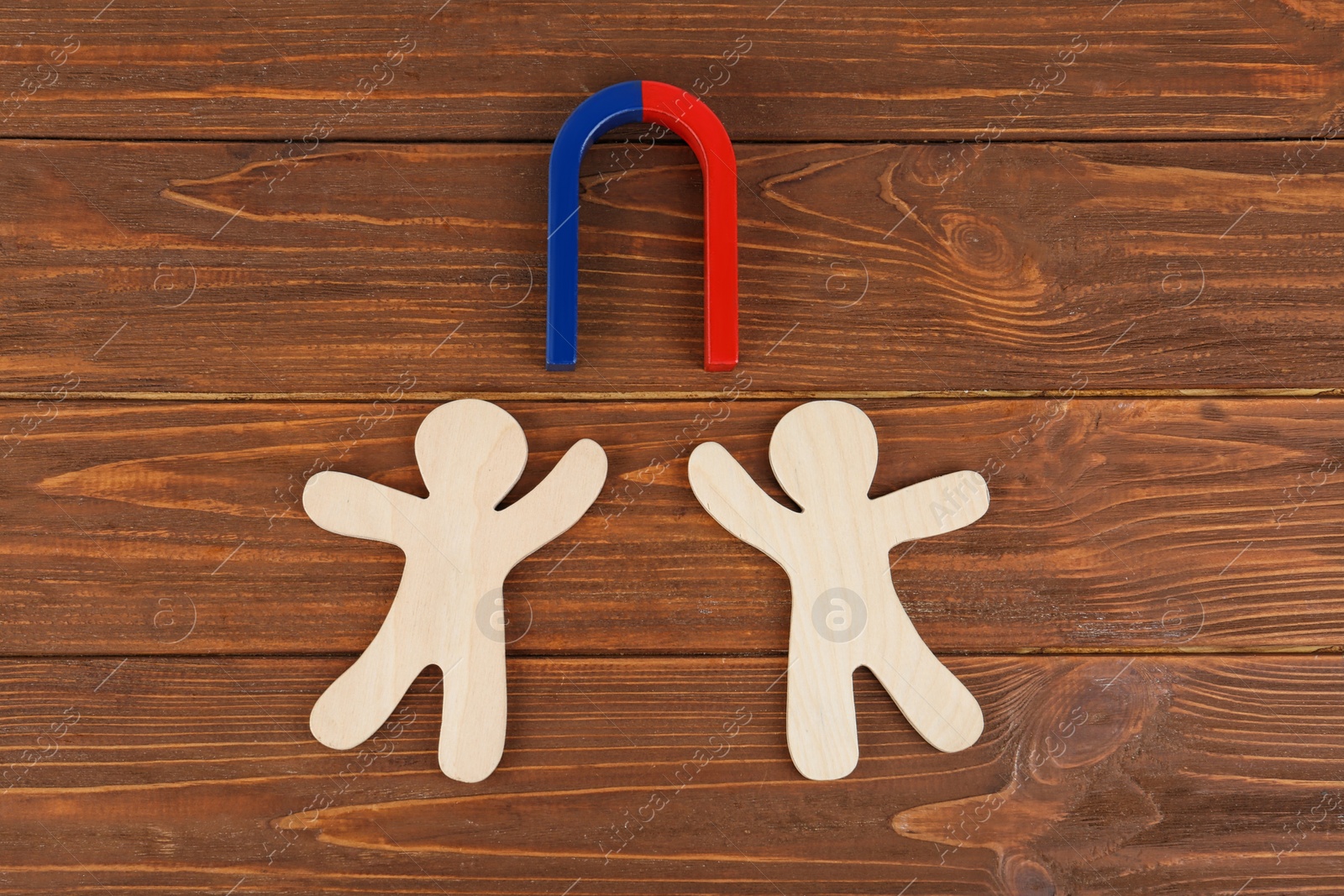 Photo of Magnet and paper people on wooden table, flat lay