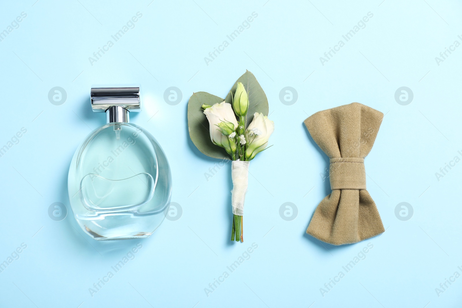 Photo of Wedding stuff. Stylish boutonniere, bow tie and perfume on light blue background, flat lay