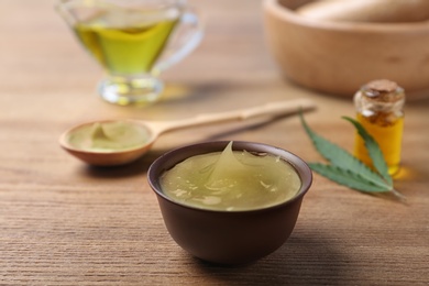 Photo of Bowl with hemp lotion on wooden table