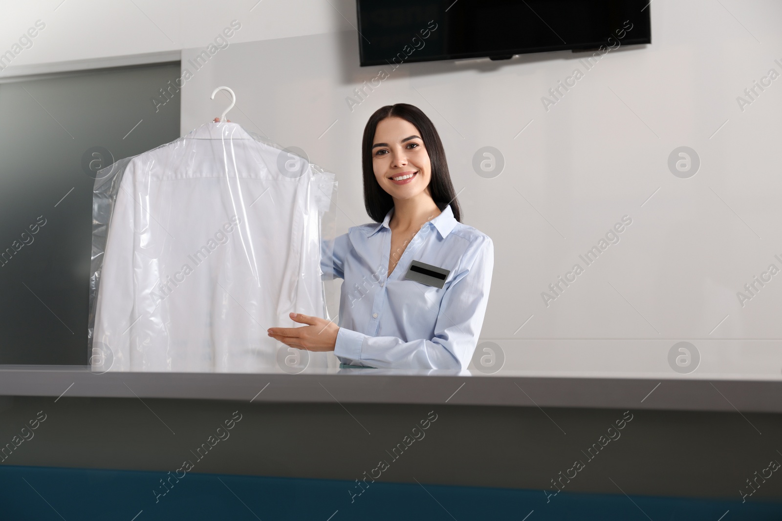 Photo of Female worker with shirt at modern dry-cleaner's