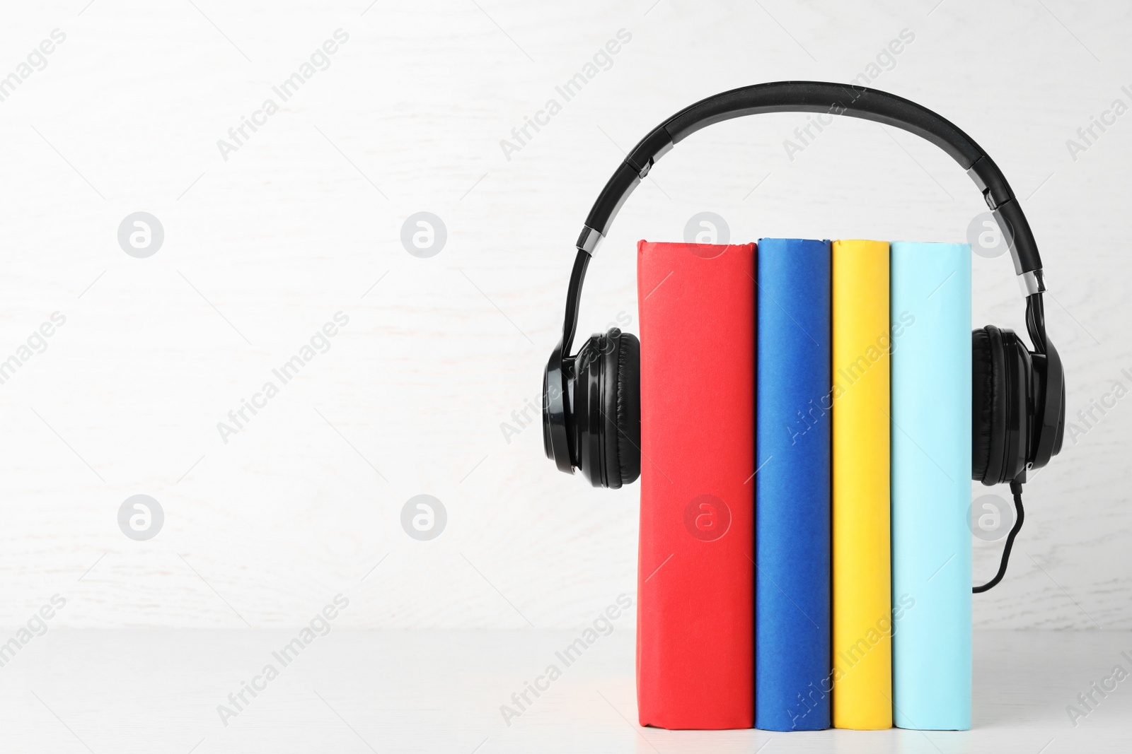 Photo of Books and modern headphones on white table. Space for text