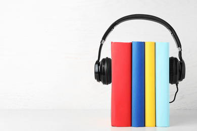 Books and modern headphones on white table. Space for text