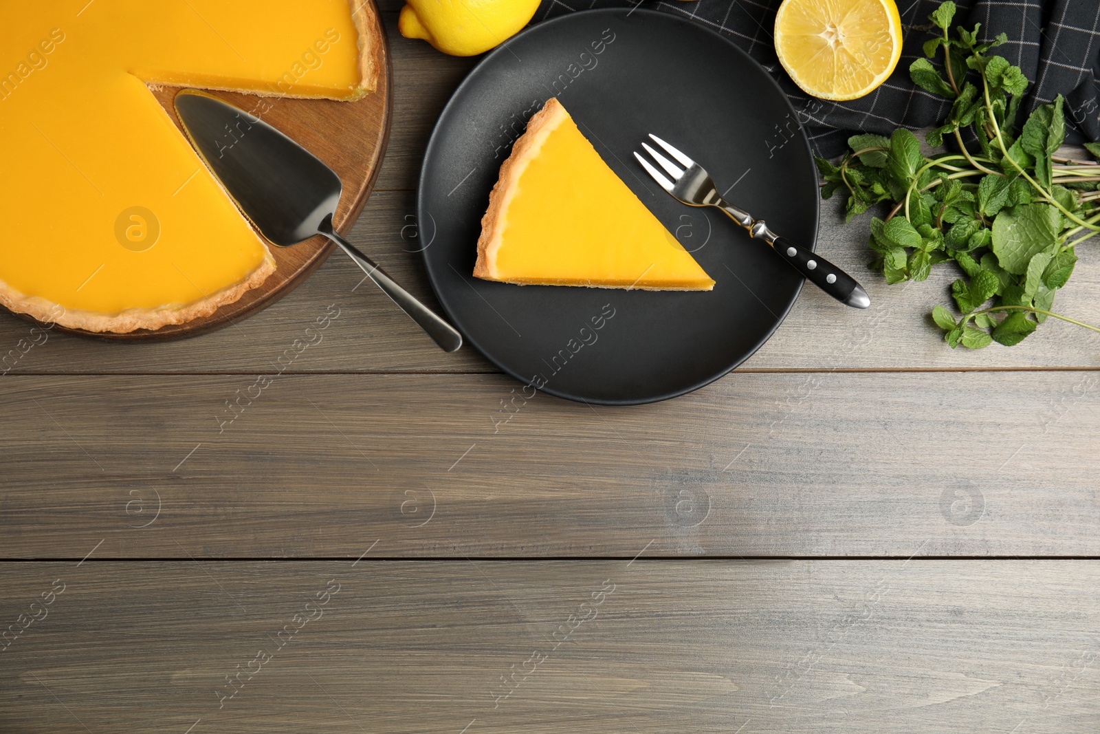 Photo of Delicious homemade lemon pie, fruits and mint on wooden table, flat lay. Space for text