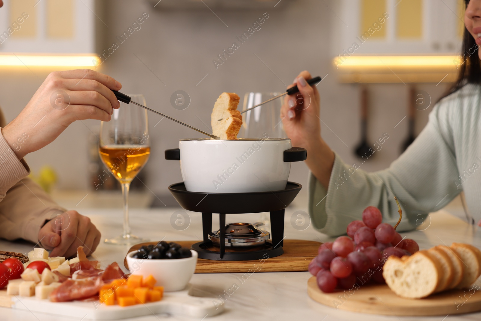 Photo of Couple enjoying fondue during romantic date in kitchen, closeup