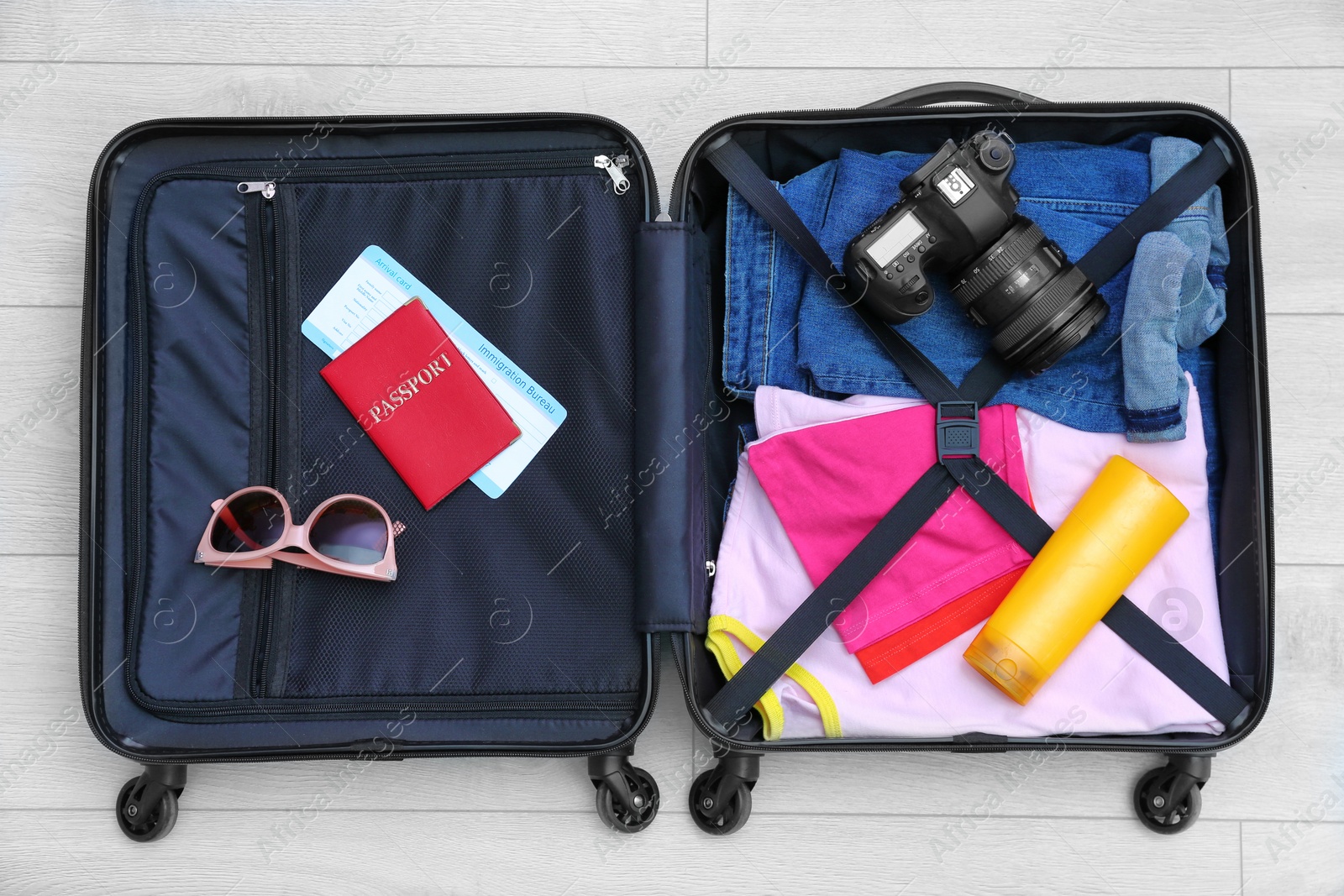 Photo of Packed suitcase on wooden background, top view
