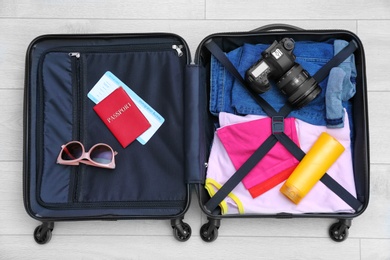 Packed suitcase on wooden background, top view