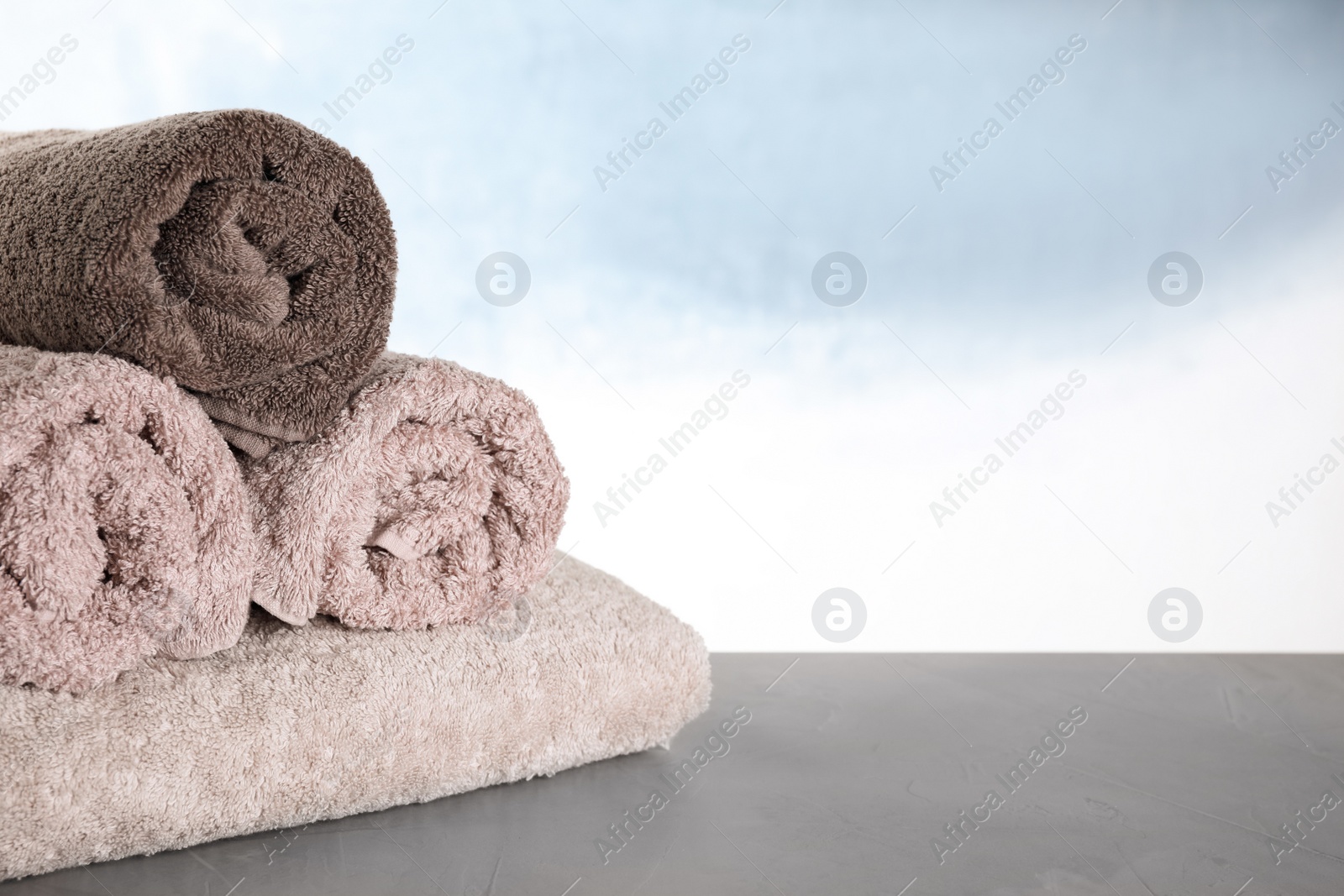 Photo of Fresh folded bath towels on grey table. Space for text