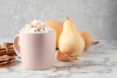 Cup with tasty pumpkin spice latte on white marble table. Space for text