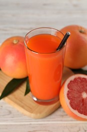 Tasty grapefruit juice in glass and fresh fruits on light wooden table, closeup