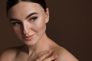 Photo of Portrait of beautiful woman with fake freckles on brown background, closeup. Space for text