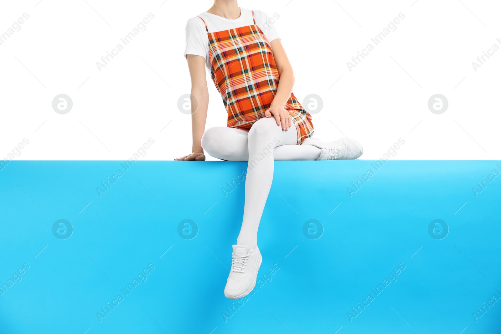 Photo of Woman wearing white tights and stylish shoes sitting on color background, closeup