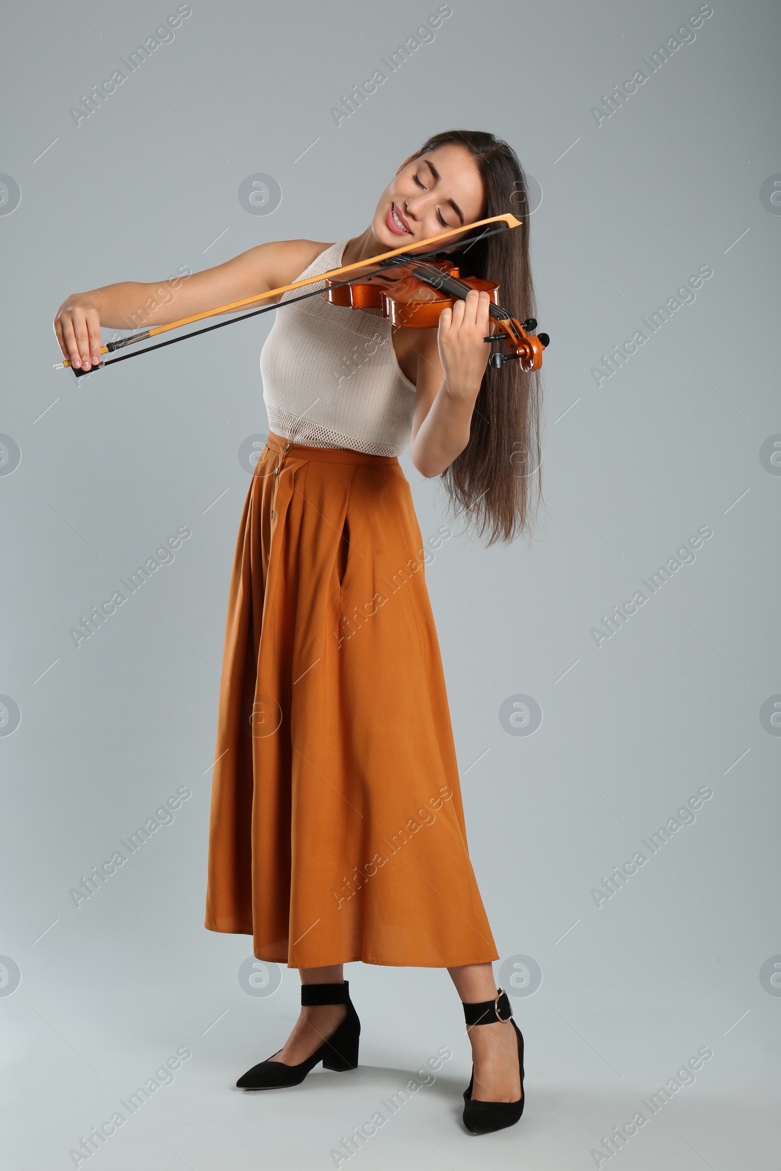 Photo of Beautiful woman playing violin on grey background