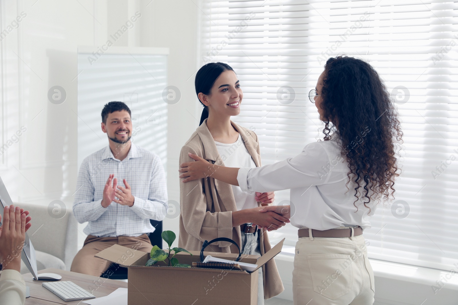 Photo of Boss shaking hand with new employee and coworkers applauding in office