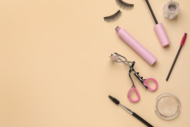 Flat lay composition with eyelash curler, makeup products and accessories on beige background. Space for text